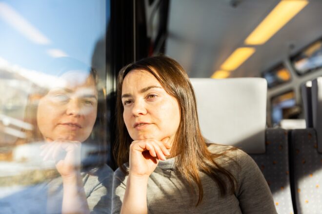 Reflective,caucasian,woman,looking,through,train,window,while,journeying.